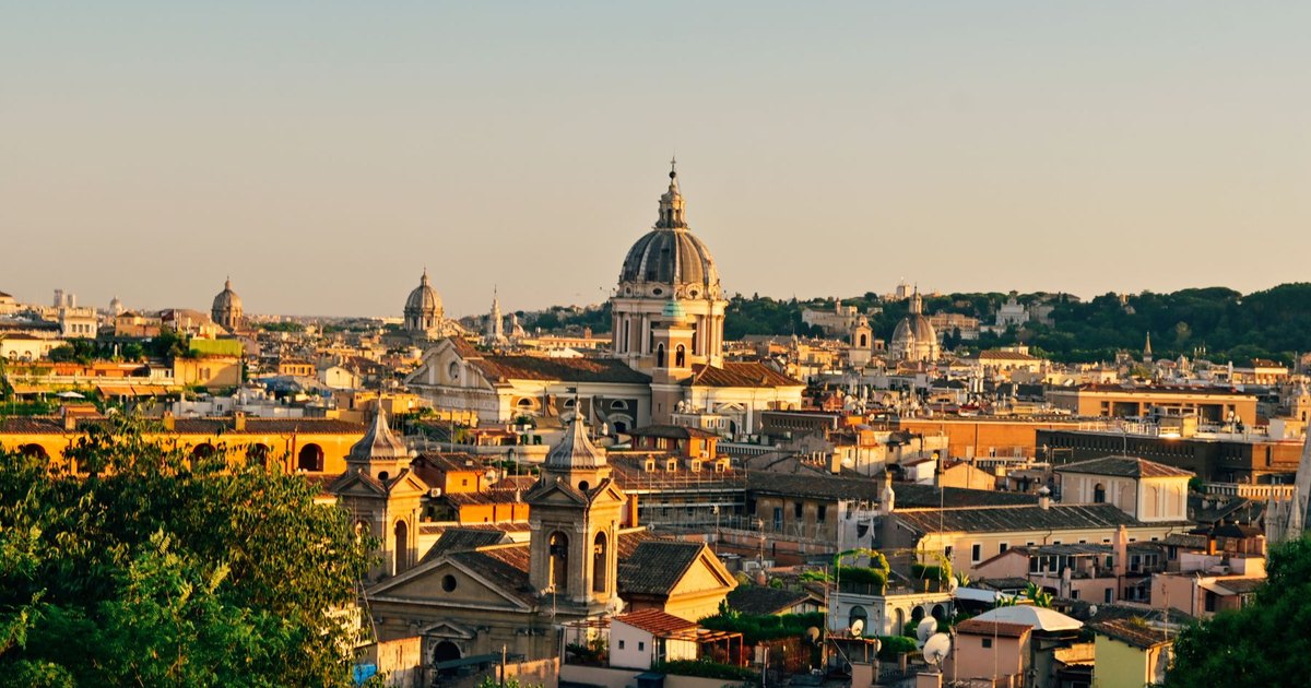 Rome's rooftops and church domes at golden hour, seen from above the old city
